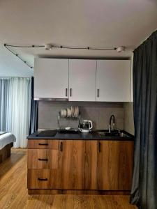 a kitchen with a sink and white cabinets and a bed at Pine Aparthotel in Shekhvetili