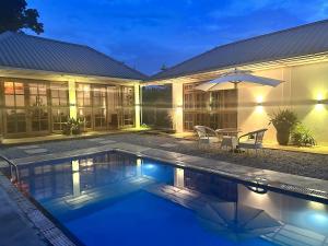 a house with a swimming pool and an umbrella at TheMalkohaVilla in Umsning
