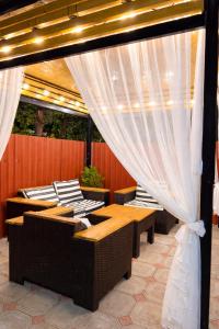 a patio with tables and chairs and curtains at Sweet Home Tskaltubo Family Guesthouse Near Spa Park in Tsqaltubo