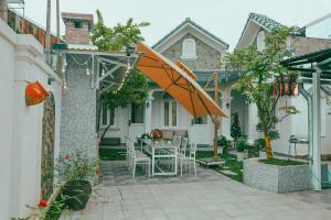 a patio with an umbrella and a table and chairs at Huế Silk Homestay in Cồn Giả Viên +9 photos