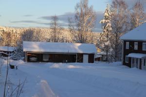 a barn covered in snow next to a house at Woxy Prilutta in Voxnabruk