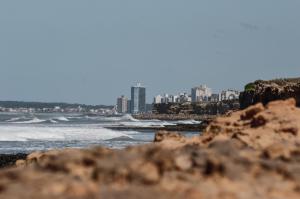 a beach with waves and a city in the background at Cabaña Zona Las Brusquitas in Miramar +2 photos
