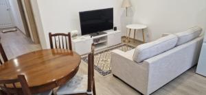 a living room with a table and a couch and a television at Casa do Arco in Aljubarrota