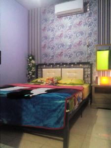 a bedroom with a bed with a purple wall at Banyuwangi Homestay in Banyuwangi