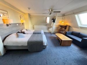 a hotel room with two beds and a couch at Hotel Dordrecht in Dordrecht