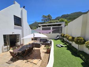 a patio with a table and chairs and an umbrella at The Gables in Hout Bay