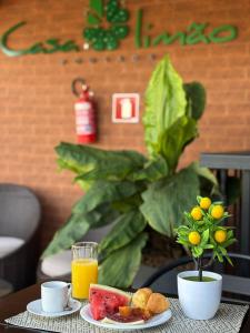 a table with a plate of food and a glass of orange juice at Pousada Casa Limão in Rifaina