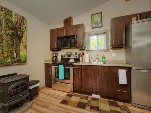 a kitchen with wooden cabinets and stainless steel appliances at Explorer's Retreat Sauna & Bunkhouse & Fire pit in Port Renfrew
