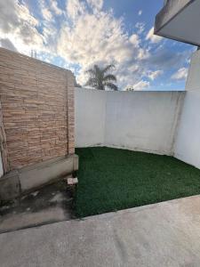 a backyard with a brick wall and green grass at Departamento temporal en Avellaneda, Santa Fe in Avellaneda