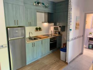 a kitchen with green cabinets and a stainless steel refrigerator at Apartamentos, Edificio Pujolets Es Pujols-Playa in Es Pujols