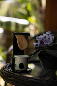 a coffee cup on a table next to a vase of purple flowers at Recanto do Rio Chalé na Natureza in Rio dos Cedros +6 photos