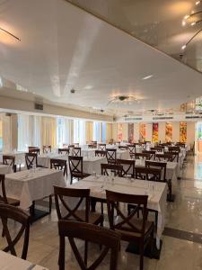a dining room with white tables and wooden chairs at Kinorot Hotel in Tiberias