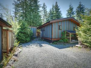 a home with a blue building in the woods at Hot Tub - Large Fully Enclosed deck - Pet Friendly in Port Renfrew