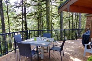 a table and chairs on a deck with trees at Hot tub Oasis Among Trees - Pet Friendly in Port Renfrew