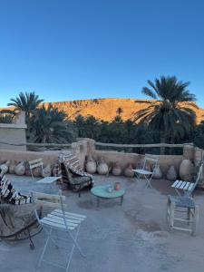 a patio with chairs and tables and palm trees at GITE LA GROTTE VALLEE in Aoûtouss