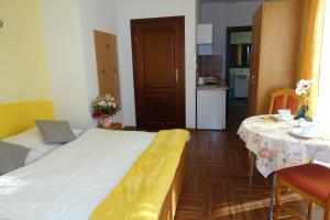 a bedroom with a bed and a table and a kitchen at Apartamenty u Ani in Kudowa-Zdrój