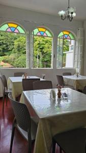 a dining room with tables and stained glass windows at Pousada Villa Real in Sabará