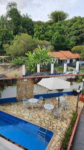 a patio with an umbrella and chairs and a pool at Pousada Villa Real in Sabará