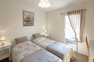 two beds in a bedroom with a window at Le Bristol in Dinard