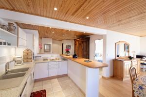 a kitchen with white cabinets and a wooden ceiling at Le Bristol in Dinard