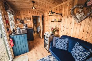 a living room with a blue couch in a cabin at The Swallow Shepherds Hut at Bee Happy Breaks Scotland in Perth
