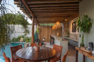 a patio with a wooden table and chairs and a pool at Villa Meraki in Pipa