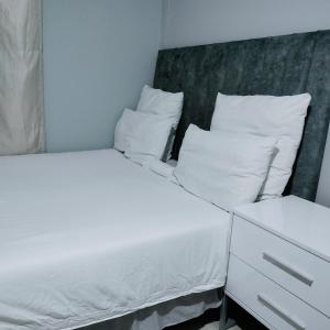 two beds with white sheets and pillows in a room at N2 Village BnB in Hadi +3 photos