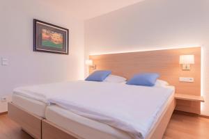 a bedroom with a large white bed with blue pillows at Hotel Gästehaus Hirsch in Remseck-Pattonville