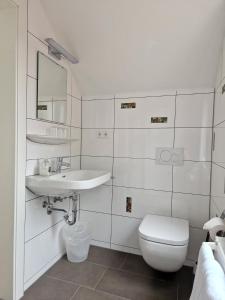 a white bathroom with a toilet and a sink at Hotel Gästehaus Hirsch in Remseck-Pattonville +12 photos