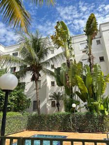 a building with palm trees and a swimming pool at Apartamento próximo Santa Casa e ABQM in Araçatuba