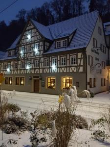 a large house with lights on in the snow at Hotel Gästehaus Hirsch in Remseck-Pattonville