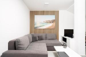 a living room with a gray couch and a painting at Apartments M&L in Vodice