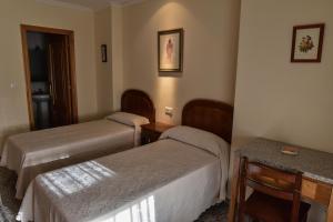 a hotel room with two beds and a table at Casa Palomin in Ourense