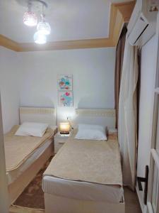 a small bedroom with two beds and a lamp at Blue Wave in Alexandria