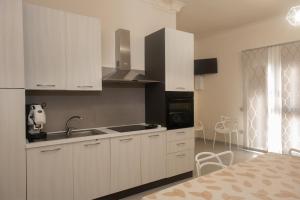 a kitchen with white cabinets and a sink at ASARO Camere in Campobello di Licata