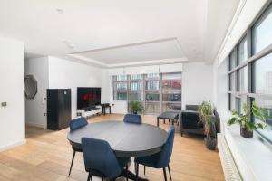 a living room with a table and blue chairs at Cozy and Spacious Central London room in Canary Wharf Flat with a City View & a Private Bathroom in London