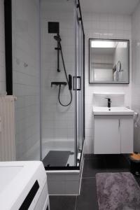a white bathroom with a shower and a sink at Appartement Wim in Blankenberge +9 photos
