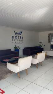 a living room with two white chairs and a couch at Hotel Estação Brejal in Brejo Santo