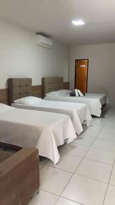 two beds in a hotel room with white sheets at Hotel Estação Brejal in Brejo Santo