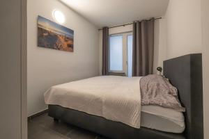 a bedroom with a large bed with a window at Appartement Wim in Blankenberge