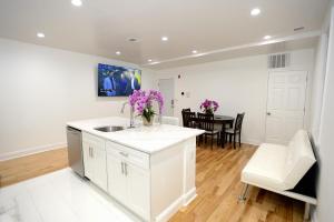 a kitchen with white cabinets and a table with purple flowers at Spacious and Brand New Apartment in Point Breeze - Prime Location in Philadelphia