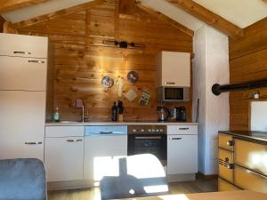 a kitchen with white appliances and a wooden wall at Sonnberg Apartment in Niedernsill +69 photos