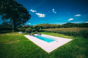 a swimming pool in the middle of a grassy field at Paineira Vila Flat in Paraisópolis