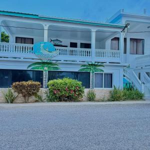 a white building with palm trees in front of it at Fernando'S Seaside Guest House in Sarteneja