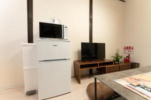 a kitchen with a microwave on top of a refrigerator at JPtrad 葵 なんばや心斎橋にも直結の8名様まで宿泊可能の広々メゾネット in Osaka