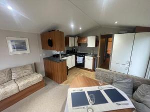 a living room with a couch and a kitchen at 26 The Green Captains Cabin in Crantock