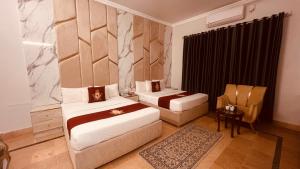 a hotel room with two beds and a chair at Hazelton in Islamabad