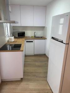 a kitchen with white cabinets and a sink and a refrigerator at Casa do práctico in Foz +5 photos