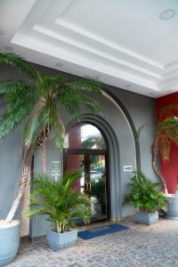 a lobby with palm trees inront of a door at New Life Piracicaba by Atlantica in Piracicaba