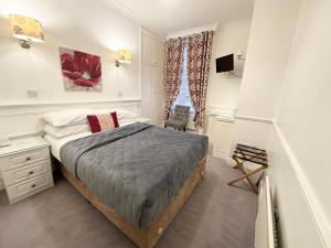 a bedroom with a bed and a desk and a window at Dergvale Hotel in Dublin